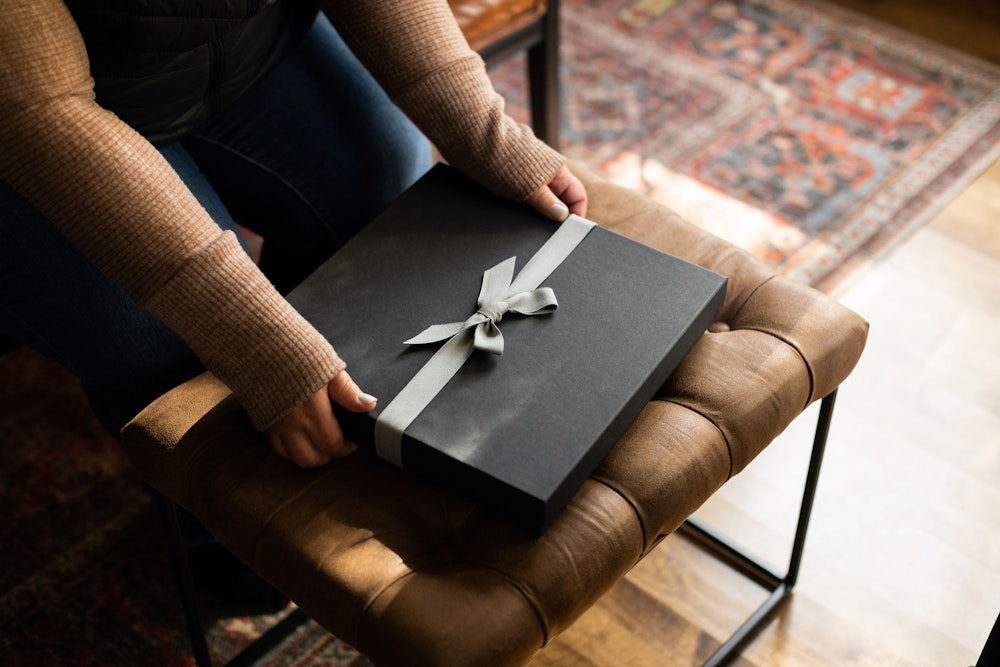 Premium Packaging Charcoal on Tufted Bench With Hands Holding Edges