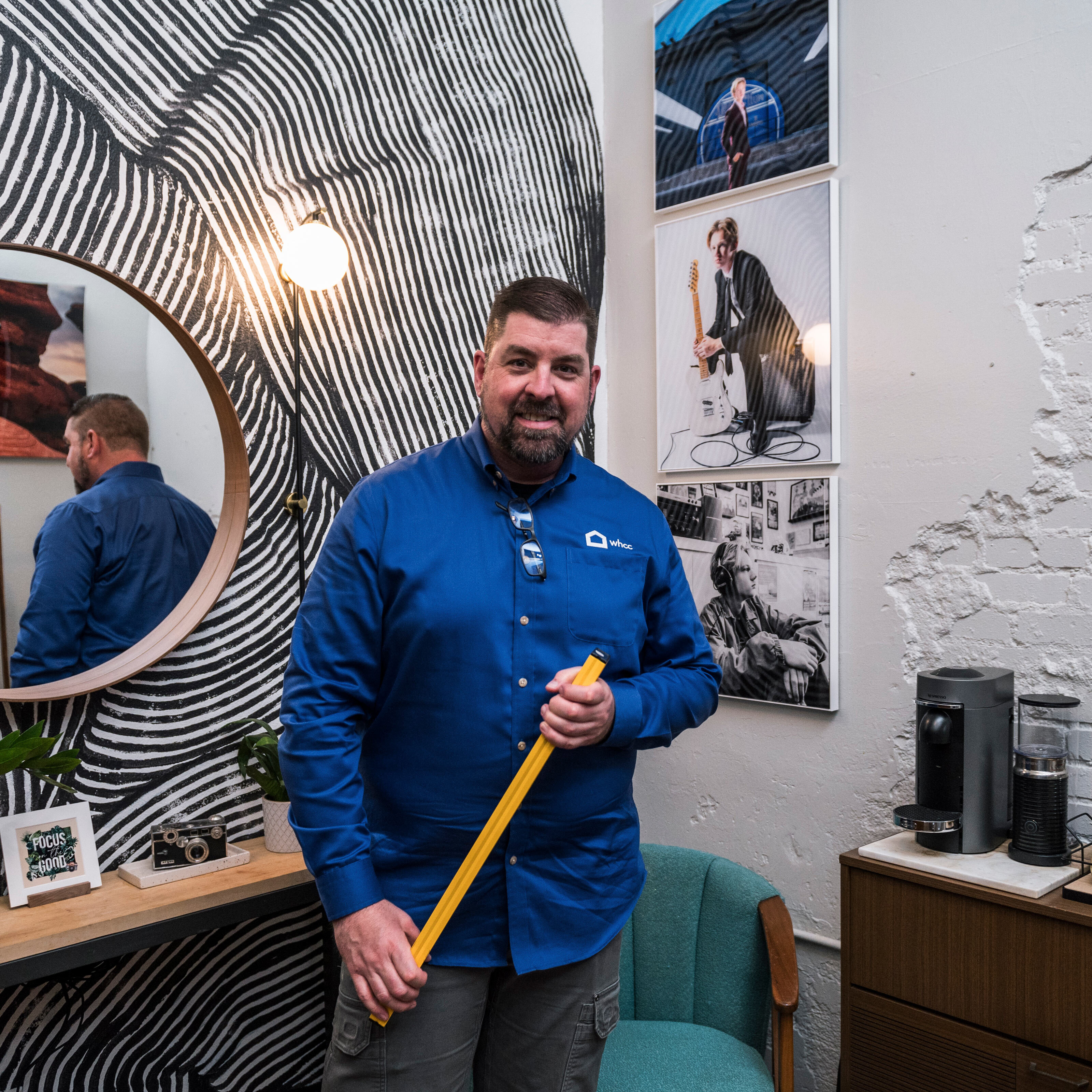 a person with a level standing in front of a collection of photography wall art