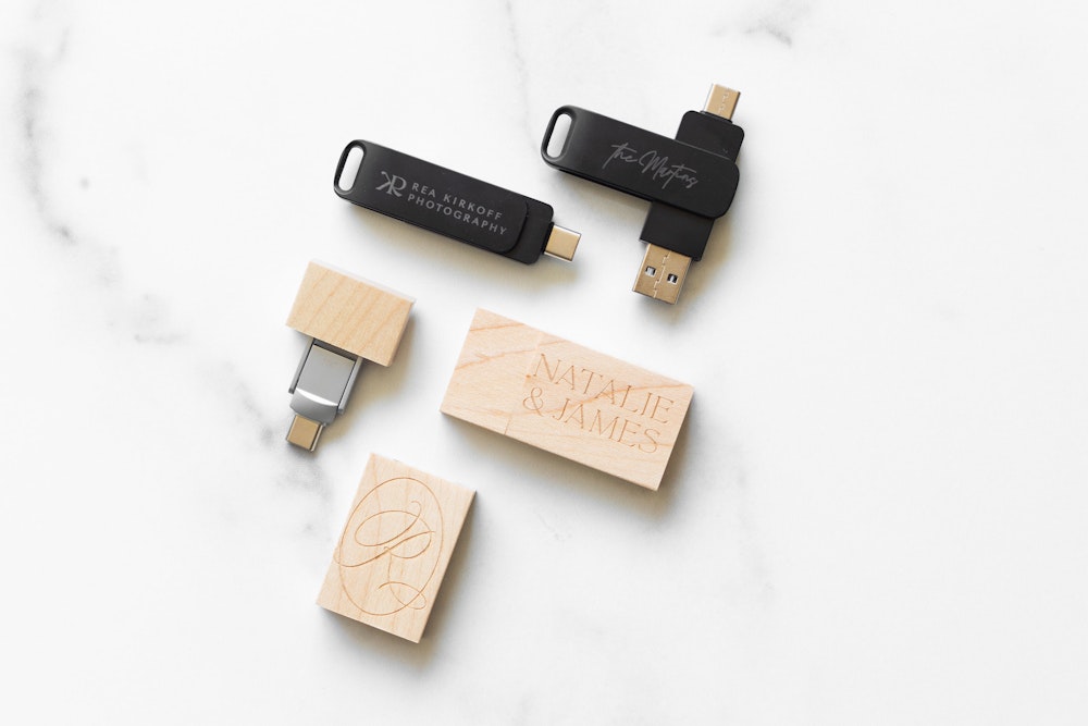 Engraved wood and metal USB drives arranged open on a marble surface