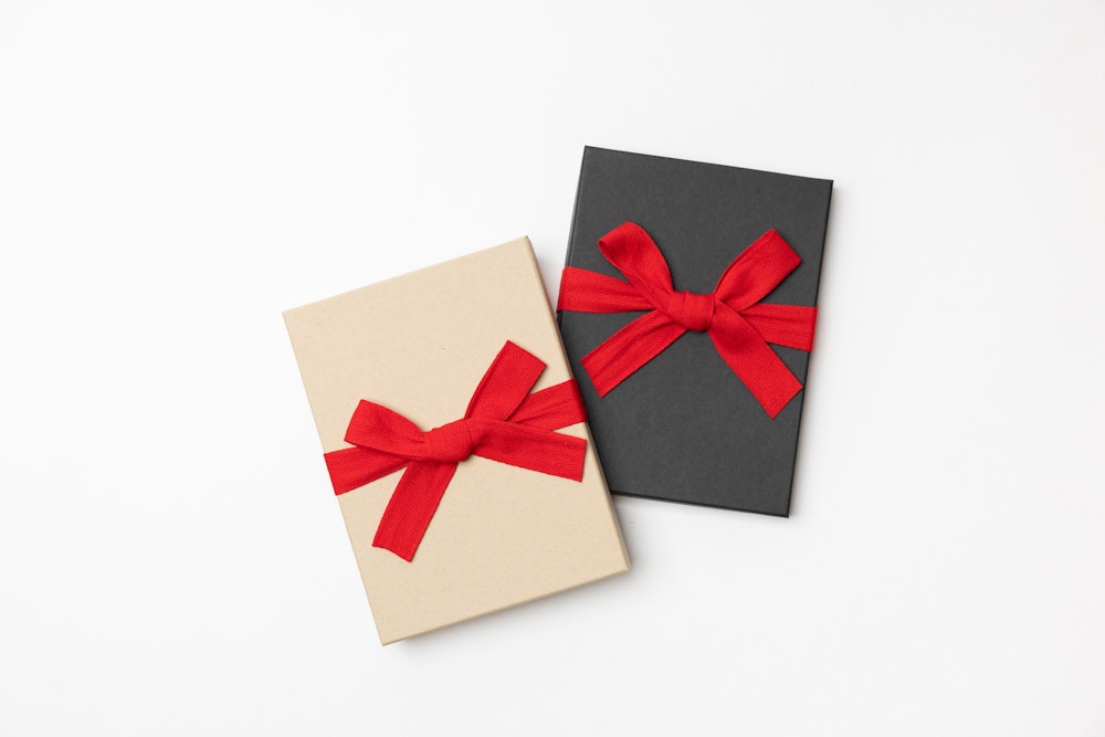 Kraft and Charcoal Premium Packaging boxes with seasonal red ribbon on a white background.