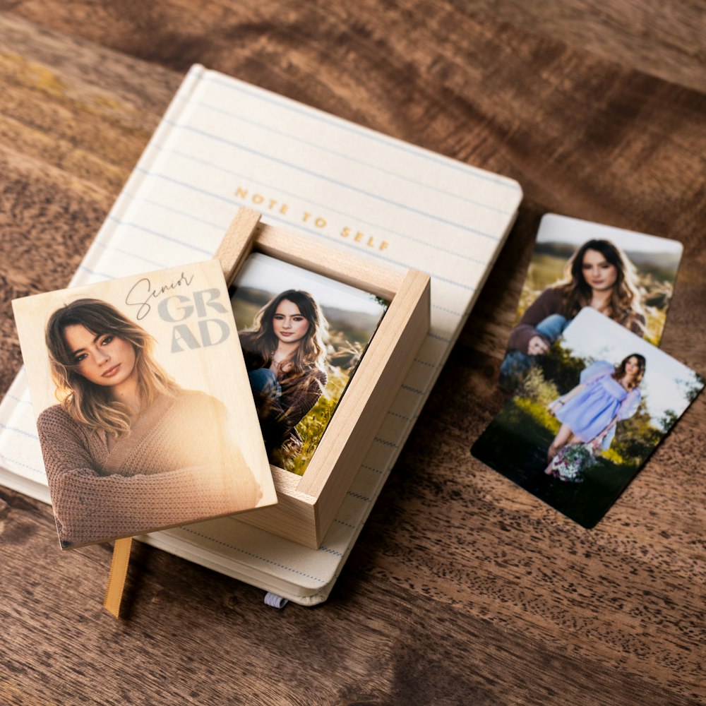 Senior portrait wallets next to and stored in a wallet-sized Wood Box on a small lined notesbook on a walnut wood tabletop
