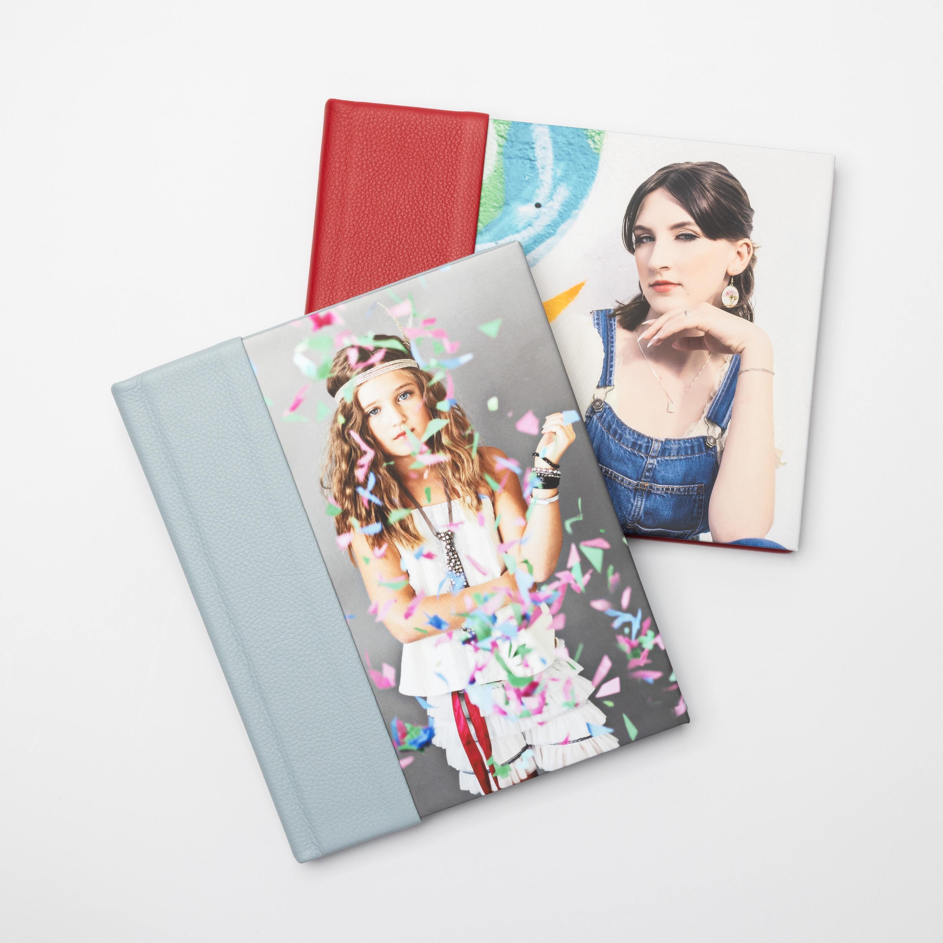 A 8×10 Cranberry Premier Leather Combo cover Album with a high school senior and Blue Heron Premier Leather Combo cover Layflat Book lay flat on a table.