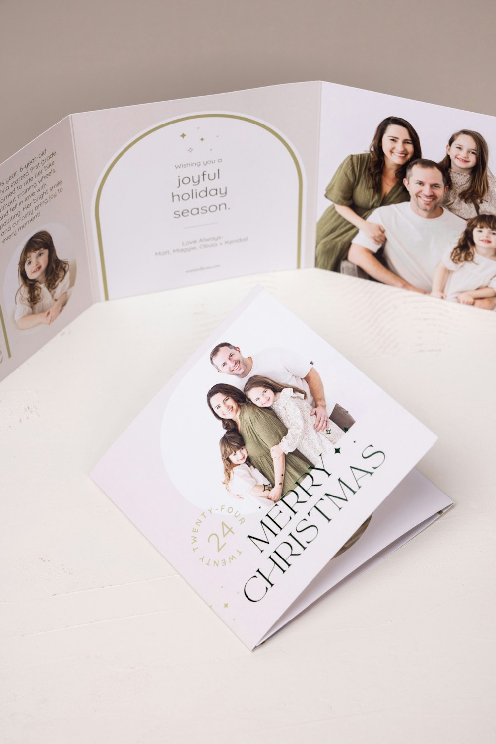 Family portraits printed on 5×5 Trifold Card with everygreen foil-pressed "Merry Christmas" design on a cream surface