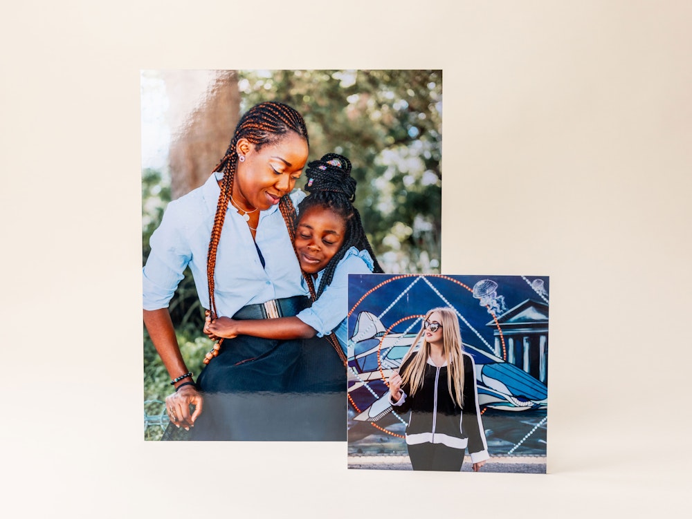 Two photo prints on Fuji Pearl paper are displayed side by side: one shows a person with braids hugging a child outdoors, and the other features a person with long blonde hair posing in front of a colorful mural.