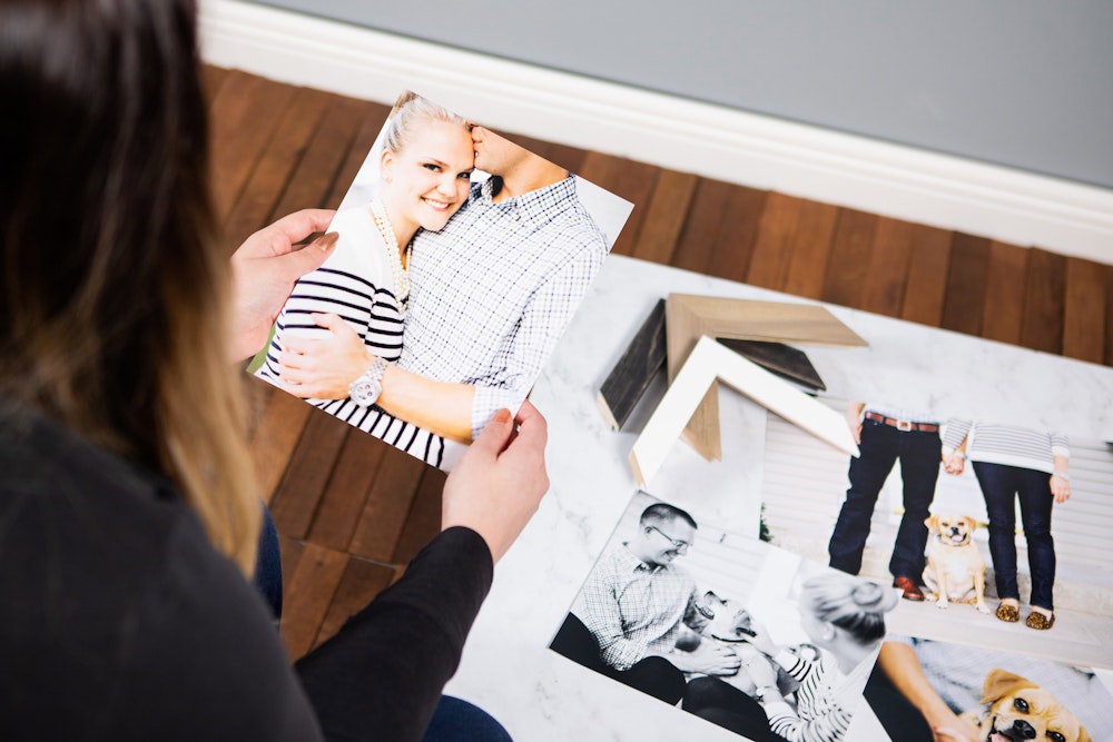 Woman holding photo prints with frame samples during sales session