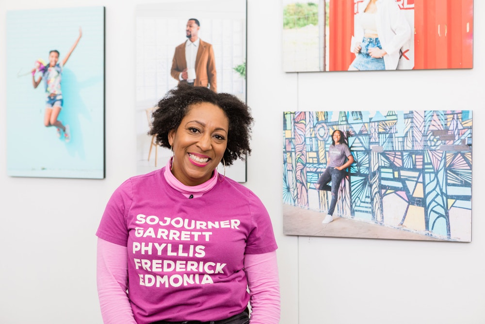 Tomayia Colvin standing in front of wall art collage featuring her portrait photography