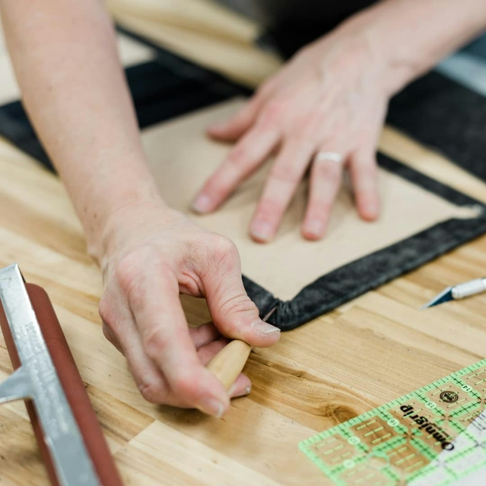 An individual wrapping the corners of the premium leather photo album cover during production.