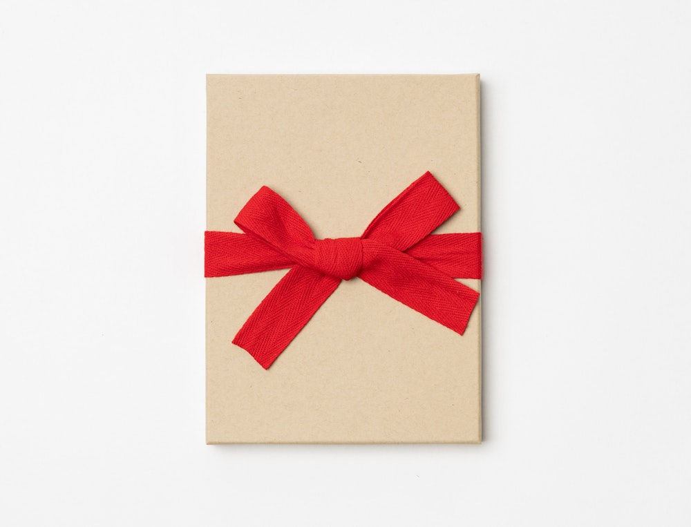 Kraft Premium Packaging box with a red ribbon tied in a bow on a light gray background
